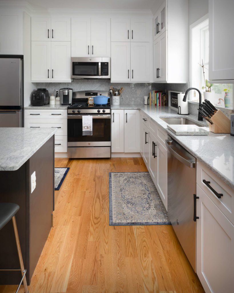 View of work surfaces featuring full height cabinets, matching drawer fronts, matching granite backsplash, and custom granite cutting board near sink in new kitchen and bathroom project in Middletown.