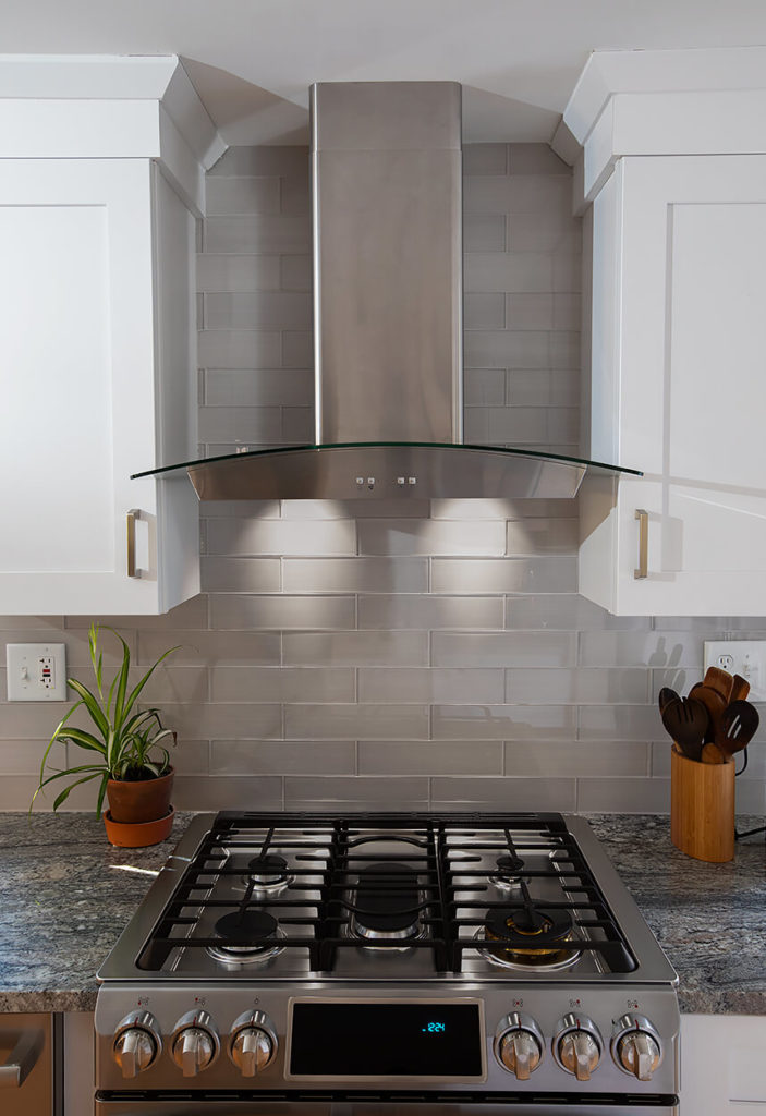 Custom glass range hood with custom upper cabinets designed to match.